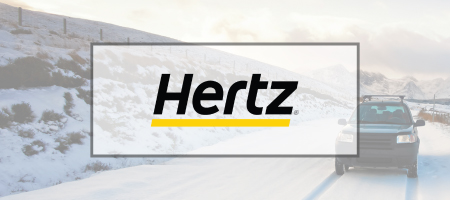 Image of the a car driving on snow behind the Hertz logo