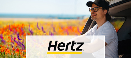 Hertz logo over an image of a man sitting and smiling in a car